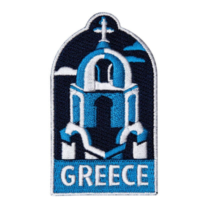 An embroidered patch featuring a blue and white Greek church dome with a cross on top and the word 'GREECE' in white on a blue banner at the bottom, shown on a plain white background.