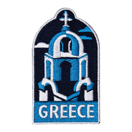 An embroidered patch featuring a blue and white Greek church dome with a cross on top and the word 'GREECE' in white on a blue banner at the bottom, shown on a plain white background.