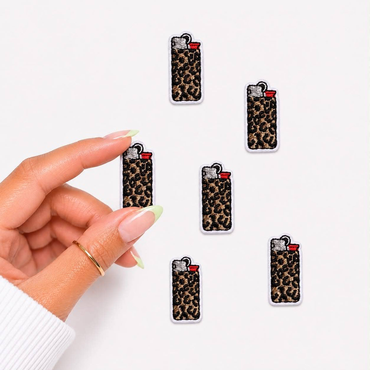 Leopard print lighter-shaped earrings held by a hand on a white background