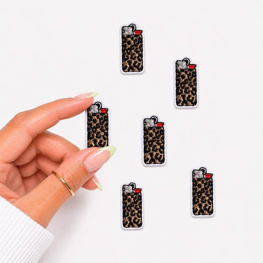 Leopard print lighter-shaped earrings held by a hand on a white background