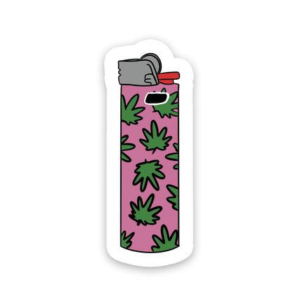 A die-cut sticker depicting a lighter with a pink body covered in green cannabis leaf patterns, shown on a plain white background.
