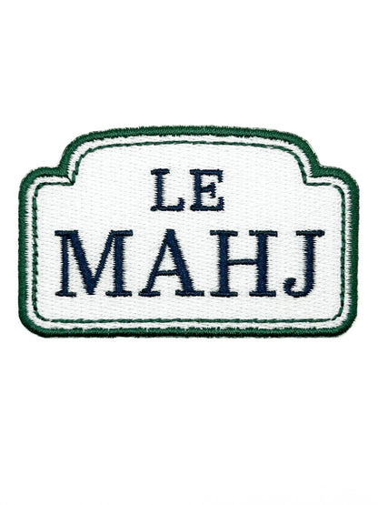 An embroidered patch with a white center, dark green border, and navy blue text reading 'LE MAHJ' on a plain white background.