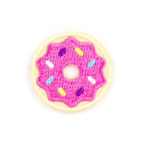 An embroidered donut patch with bright pink frosting, multicolored sprinkles, and a beige outer border on a plain white background.