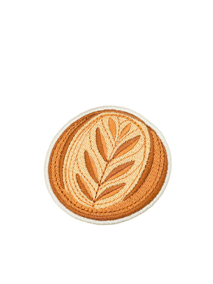 A circular embroidered patch featuring a sourdough bread design in shades of orange, tan, and cream, finished with a white border, shown on a plain white background.